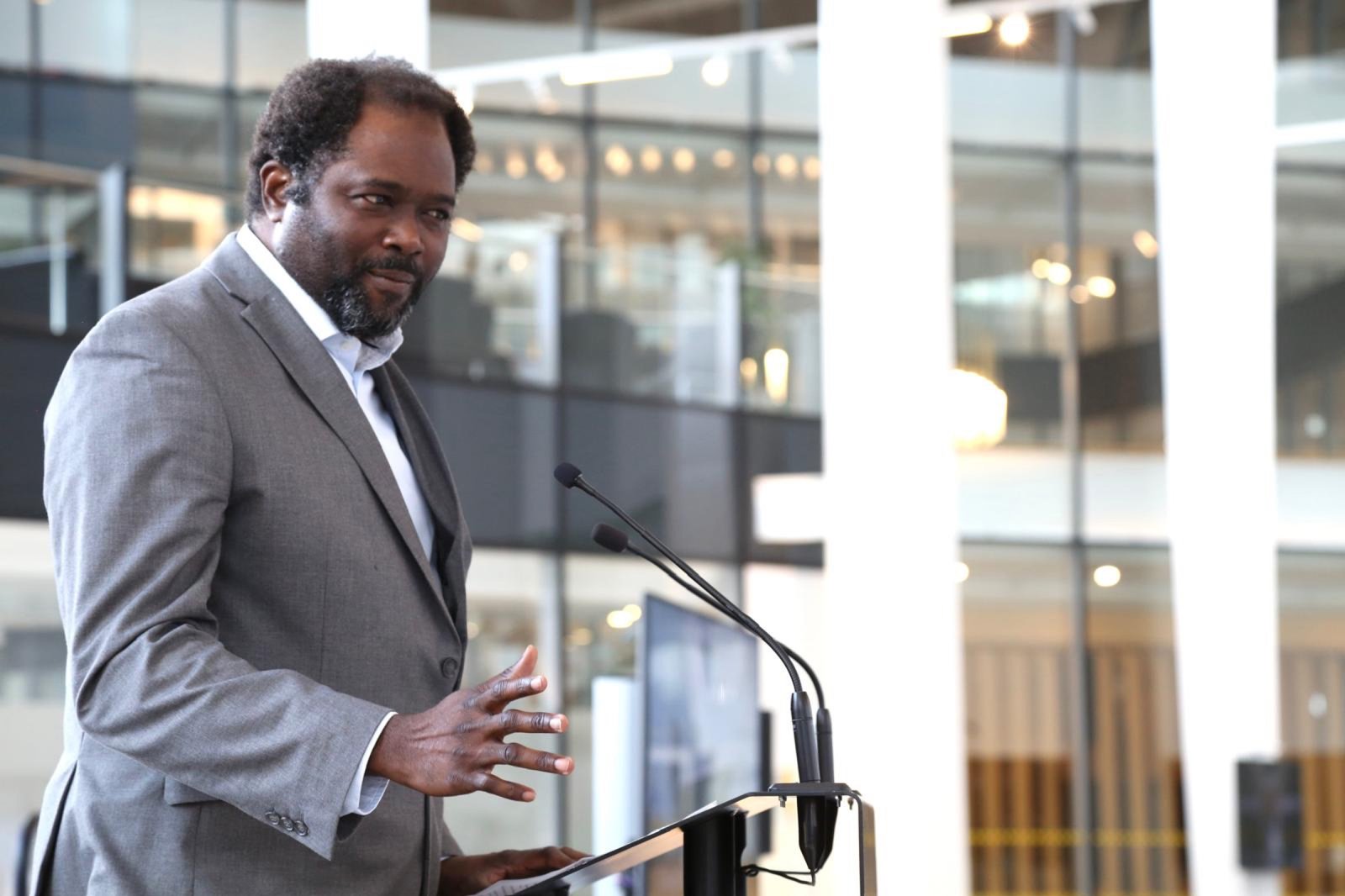 Ayo Akande speaking in a glass atrium