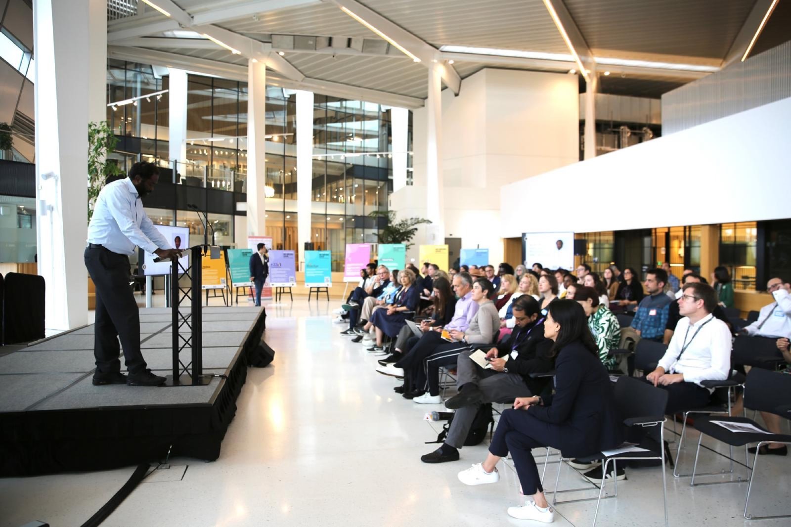 Ayo Akande speaking from a stage to a seated audience